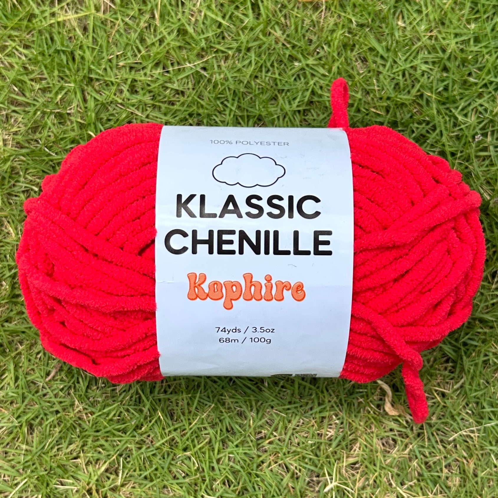 Red skein of yarn with a label on grass