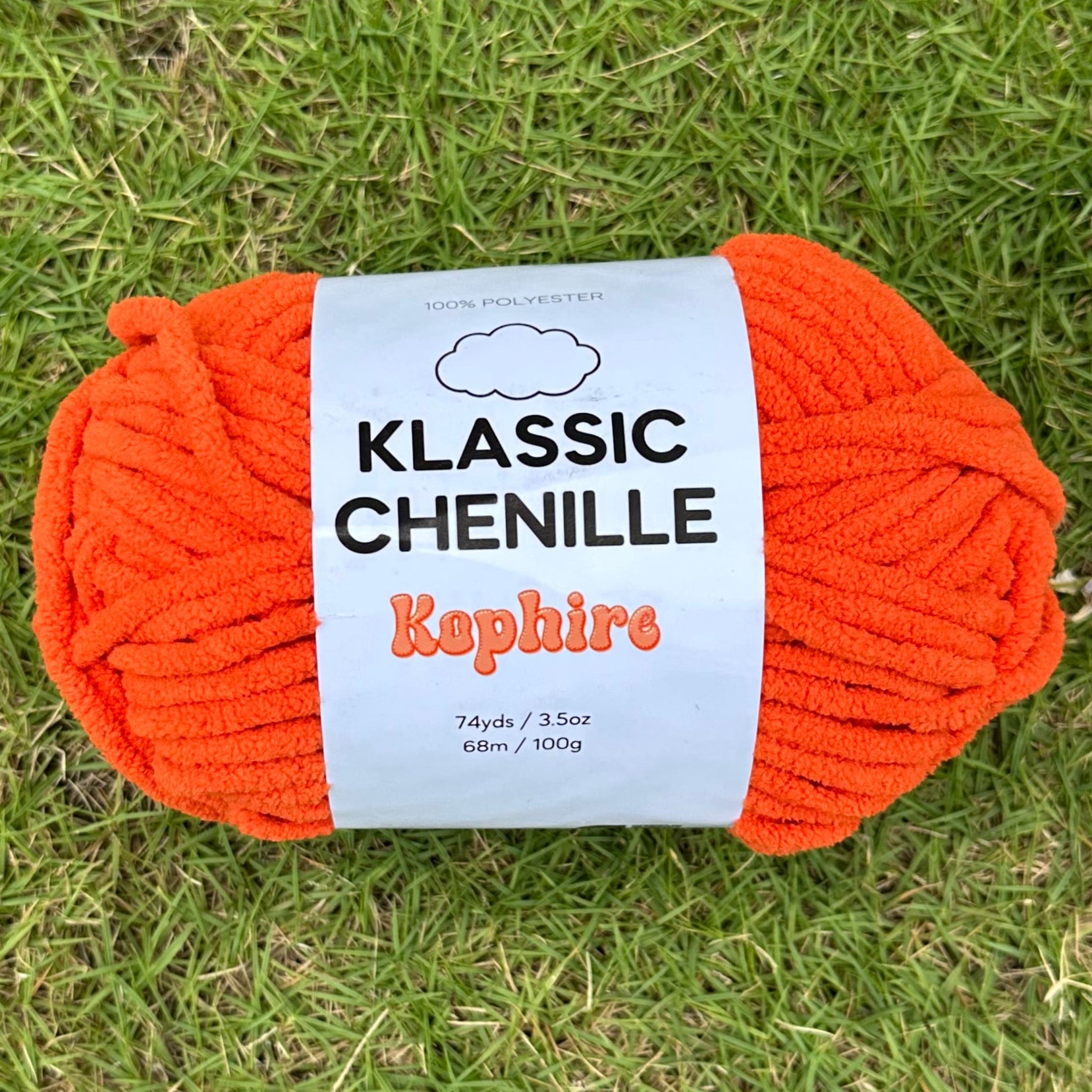 Orange ball of yarn with a label on grass