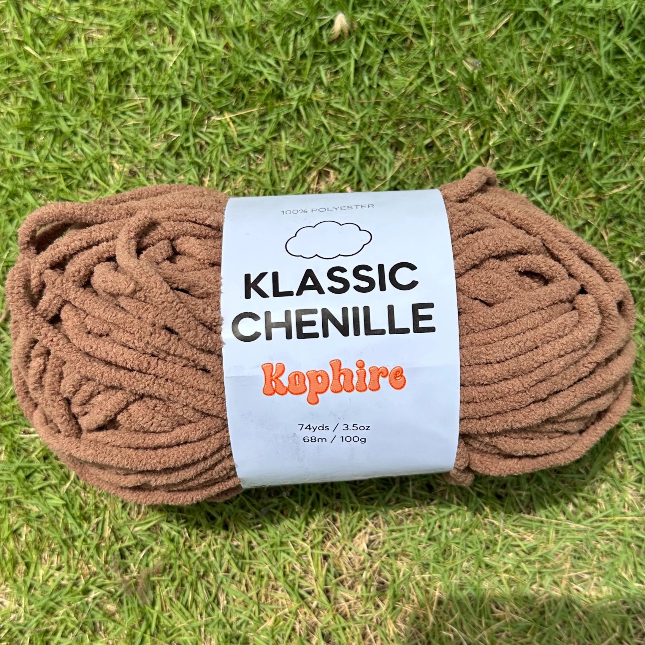 Ball of brown yarn with a label on a grassy background